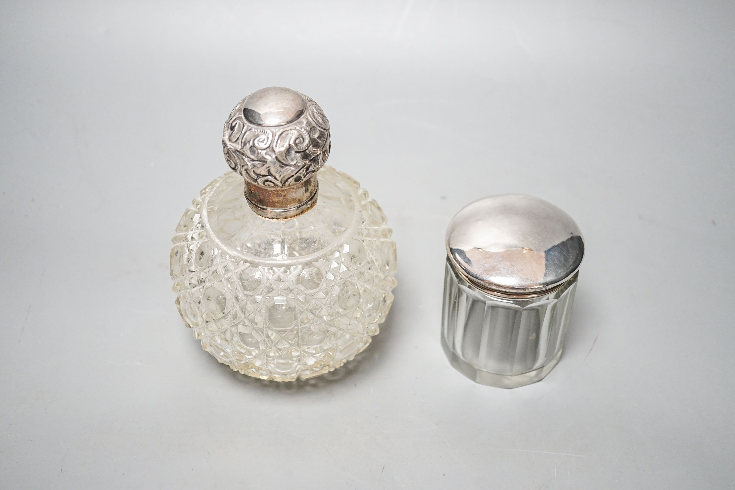An Edwardian silver topped cut glass globular scent bottle, Birmingham, 1906, 15.3cm and a silver topped toilet bottle.